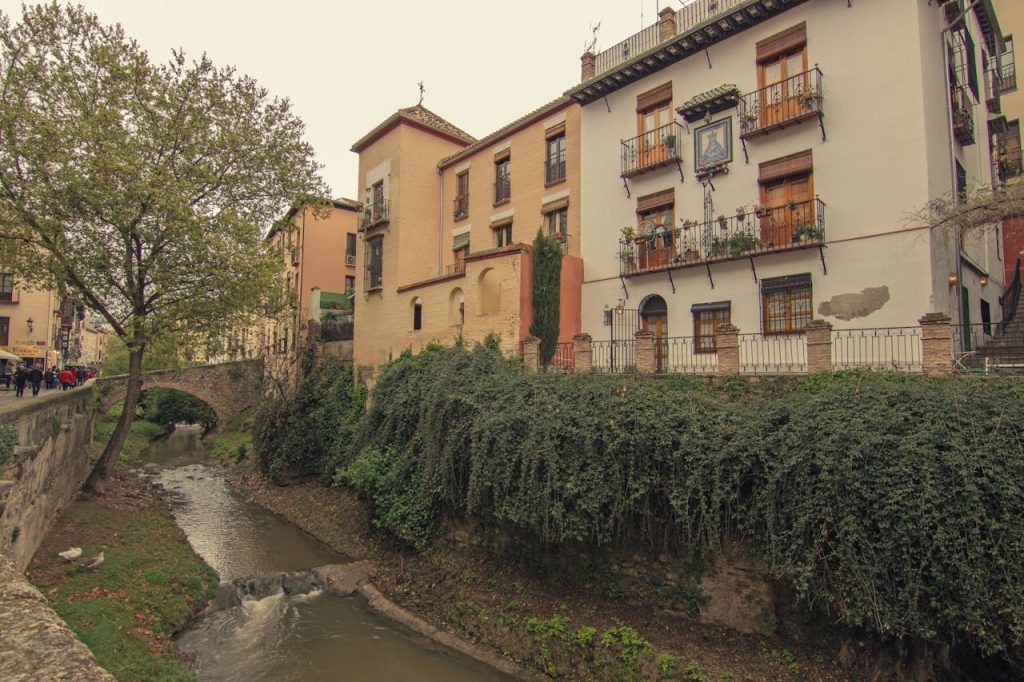 Picturesque view of historic buildings along a river in Granada, Spain.